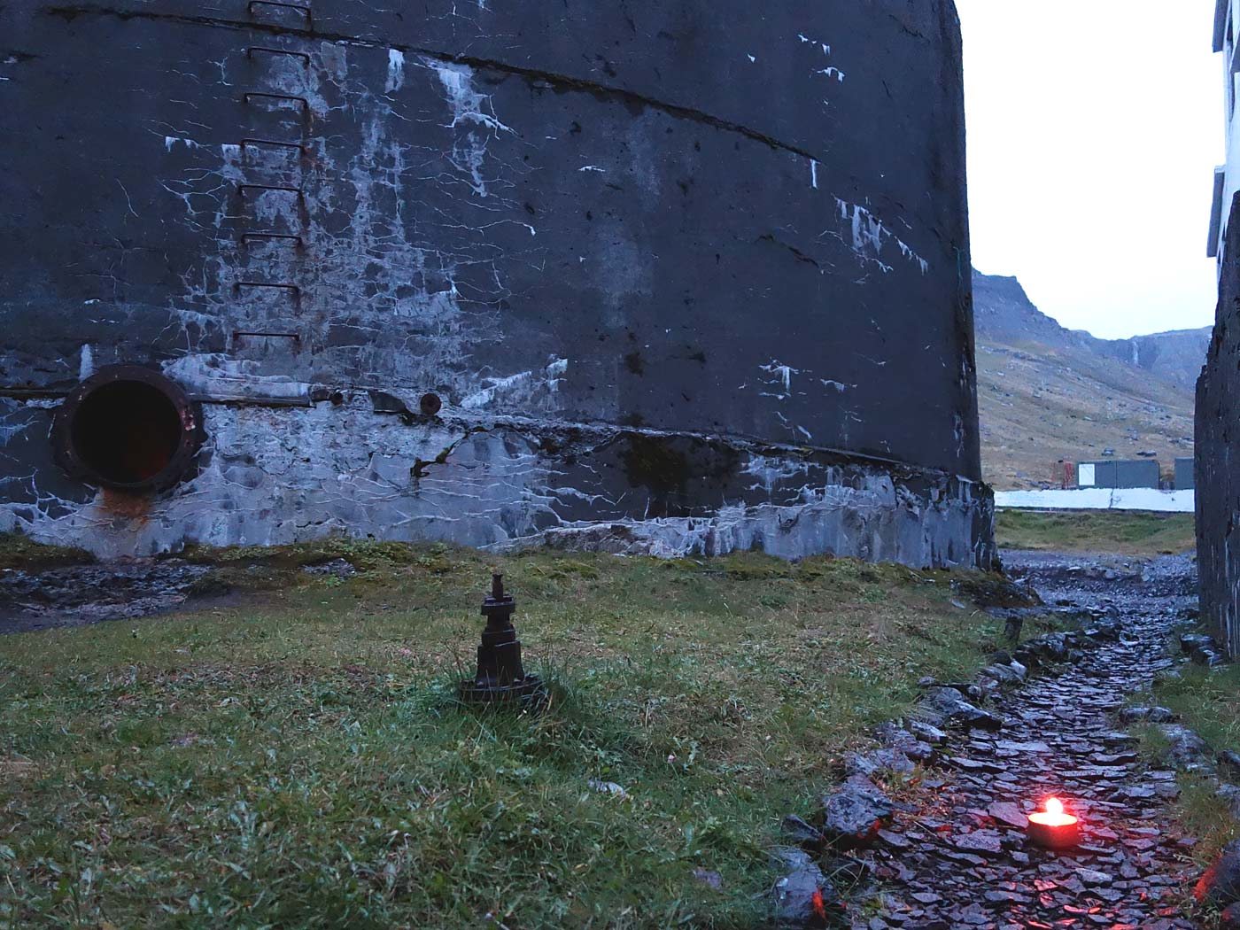 Djúpavík. Konzert mit Vokalistin Anna Jónsdóttir. - Der Bereich vor der Konzerthalle - einem Betontank, in welchem Heringöl gelagert wurde, direkt neben der alten Heringfabrik. Links der Eingang - ein rundes Loch ... (10.08.2013)